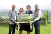 Hannes Hofmüller, Barbara Schwarz, Landesrätin Michaela Langer-Weninger und Manfred Ettinger stehen nebeneinander auf einem gartenartigen Gelände und halten gemeinsam ein kleines Holzbankerl mit Blumen sowie das Plakat zur OÖ Gartenzeit