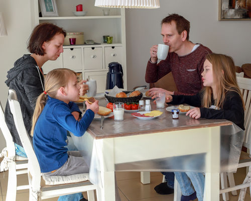 Die Eltern sitzen mit ihren Kleinen am Frühstückstisch.