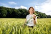 Landesrätin Michaela Langer-Weninger steht in einem Getreidefeld und hält ein drei Halme in Händen