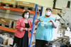 Dominik Stieger und Landesrätin Birgit Gerstorfer, beide mit Mund-Nasen-Schutz, stehen in einer Werkstätte mit Regalen, Kisten, Werkzeug