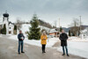 Clemens Schnaitl, Bürgermeisterin Elisabeth Feichtinger und Landesrat Stefan Kaineder vor der Kulisse des Ortsteils Reindlmühl in Altmünster, Kirche, Häuser und Straßenbeleuchtung