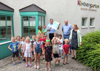 Ein Gruppe Kindergartenkinder mit ,Gerda Ellek, Landesrat Stefan Kaineder, mit Urkunde in Händen, Manfred Kalchmair und Ulrike Singer vor dem Kindergartengebäude