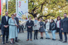 Mag. Felix Eypeltauer, Mag.a Dagmar Engl, Dr. Christian Dörfel, Landesrat Mag. Michael Lindner, Mag. a Christine Winkler-Kirchberger, Stefanie Hofmann, zwei Schülerinnen, Sabine Engleitner-Neu, MA, und Manuel Krautgartner stehen im Linzer Promenadenpark, zwischen ihnen ist die Kinderrechte-Fahne auf einem Mast zu sehen