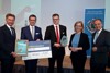 Vizebürgermeister Gerhard Kroiß, Landesrat Markus Achleitner, DI Joachim Kalkgruber, Ministerin Leonore Gewessler und Dr. Gerhard Dell stehen nebeneinander und halten Urkunde, Scheck und Preis in Händen