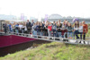 Landesrat Markus Achleitner und DI Dr. Wilfried Enzenhofer, MBA, stehen mit einer großen Gruppe Kinder auf einer Gangway  zu einem Schiff, Hintergrund Stadt, Häuser, eine Brücke über den Fluss