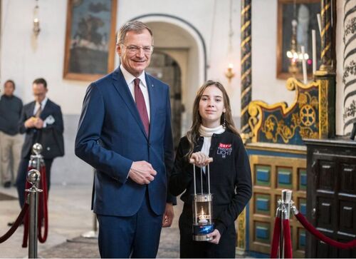 Landeshauptmann Mag. Thomas Stelzer und Sarah Noska stehen nebeneinander in einem kirchlichen Raum, das Mädchen hält eine spezielle Laterne, in der sich eine Kerze befindet, in Händen