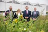 Johann Schwarzenhofer, Katrin Hohensinner, Landeshauptmann Mag. Thomas Stelzer und Landesrat Max Hiegelsberger stehen nebeneinander auf einer Blumenwiese, im Hintergrund ein Betriebsgebäude