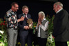 Karl Ploberger mit Mikrofon, Landeshauptmann Mag. Thomas Stelzer mit Preis in Form einer Blume und Gießkanne sowie eine ältere Dame und ein Herr stehen freudig lächelnd nebeneinander auf einer blumengeschmückten Bühne