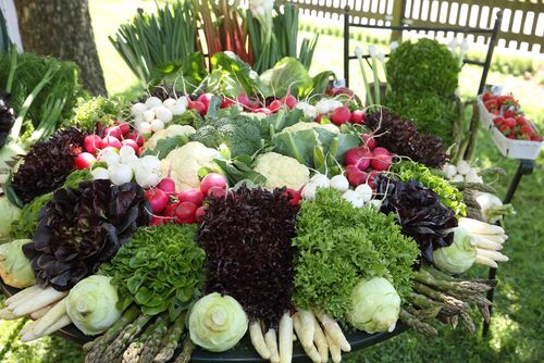 verschiedene Gemüsesorten auf einem Tisch und ein Schälchen Erdbeeren daneben