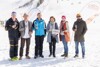 Helmut Holzinger, Dieter Eschlböck, Wirtschafts-Landesrat Markus Achleitner, Agrar-Landesrätin Michaela Langer-Weninger, Katrin Schiefermair und Michael Steininger stehend mit Weingläsern im Schnee; im Hintergrund das Skigebiet Hinterstoder und Beachflags der Wurzeralm und vom Genussland Oberösterreich.