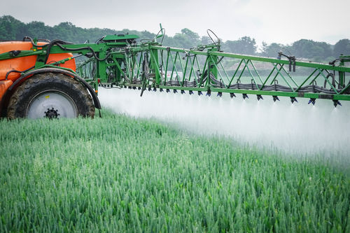 Eine landwirtschaftliche Maschine sprüht Unkrautvernichtungsmittel auf ein Feld