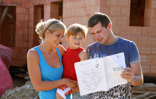 Eine Familie besichtigt die Baustelle ihres Eigenheims.