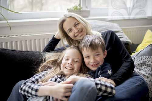 Frau mit zwei Kindern sitzend auf einer Couch.