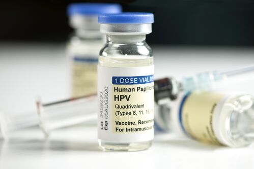 Ein kleiner Glasbehälter mit Aufschrift Human Papilloma HPV, dahinter zwei weitere Fläschchen und eine Spritze