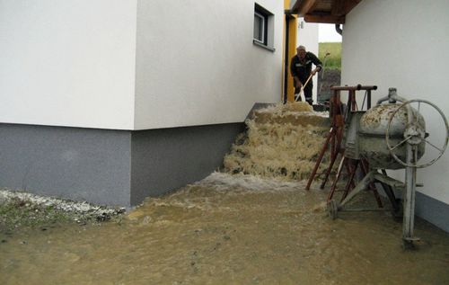 Ein Hausbesitzer kämpft mit dem Hangwasser vor seiner Wohnungstür.