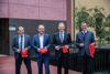 Mag. Dr. Günther Hendorfer, Gerald Hackl, Landeshauptmann Mag. Thomas Stelzer und Landesrat Markus Achleitner stehen nebeneinander auf einer kleinen Brücke vor einem Gebäude, jeder hält eine Schere und ein Stück von einem Band in Händen