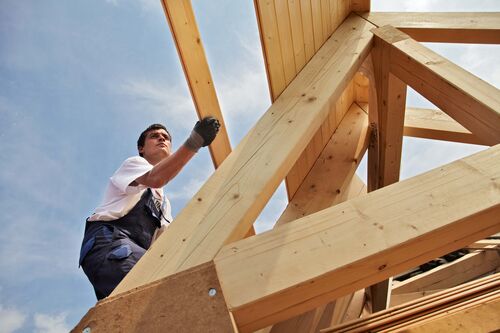 Arbeiter auf einem im Bau befindlichen Dachstuhl aus Holz 