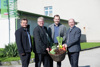 Architekt Daniel Hora, Direktor Walter Raab (LWBFS Waizenkirchen), Bürgermeister Waizenkirchen Fabian Grüneis und Agrar-Landesrat Max Hiegelsberger stehen nebeneinander vor einem Gebäude und halten gemeinsam einen Korb, der mit frischem Gemüse gefüllt ist. 