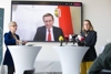 Präsidentin Mag.a Doris Hummer, LR Markus Achleitner (per Video zur Pressekonferenz zugeschaltet auf einer Vidiwall) und BM.in Dr.in Margarete Schramböck stehen jeweils an einem Stehtisch mit Mikrofonen, dahinter die Vidiwall.