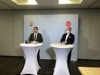 Landeshauptmann-Stv. Dr. Manfred Haimbuchner und Ing. Norbert Hartl, MSc MBA, stehen in einem Konferenzraum an zwei Stehtischen mit Mikrofonen