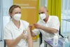 Frau wird von Mann geimpft, beide tragen FFP2-Masken