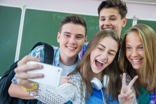 Vier Jugendliche machen ein Selfie in einem Klassenraum