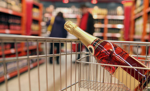 Ein Einkaufswagen mit einer Flasche Sekt im Supermarkt.