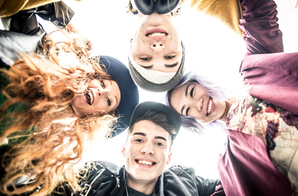 Vier Jugendliche im Kreis blicken von oben auf die Kamera herab