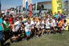 Startszene: eine große Gruppe Kinder startet zu einem Lauf, im Hintergrund Wimpel, Publikum, Parkgelände, Brucknerhaus