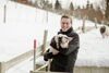 Umwelt- und Klima-Landesrat Stefan Kaineder steht in einem Schweinegehege und hält ein Ferkel in seinen Armen.