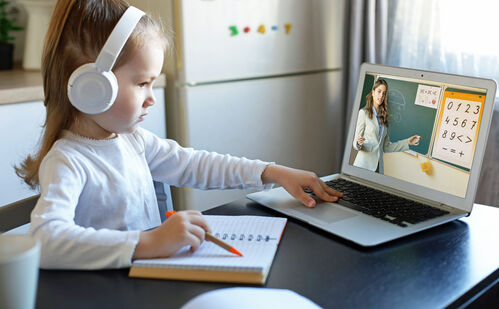 Ein Volksschulkind mit Kopfhörern lernt mit dem Laptop.