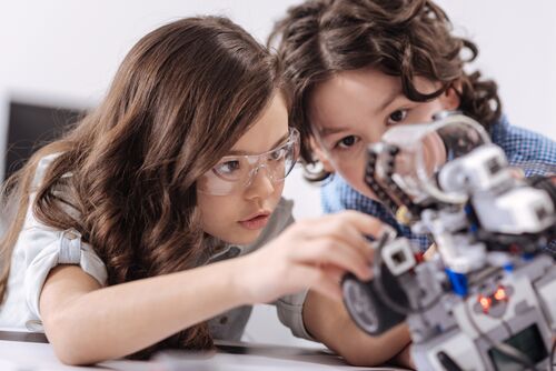 Zwei Kinder untersuchen einen Roboter