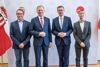 FH-Prof. DI Robert Kolmhofer, Landeshauptmann Mag. Thomas Stelzer, Landesrat Markus Achleitner und Univ.-Prof. Dr. René Mayrhofer stehen nebeneinander vor einer Fotowand mit Oberösterreich-Wappen, neben ihnen eine Oberösterreich-Fahne