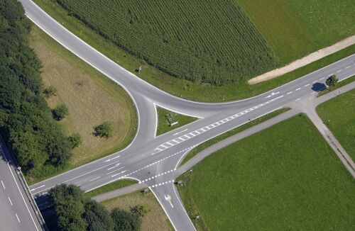 Straßenkreuzung umgeben von Grünland und Acker