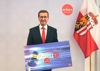 Landesrat Markus Achleitner hält ein Schild mit Beschriftung Oberösterreich sagt Adieu Öl Jetzt raus aus den Ölheizungen