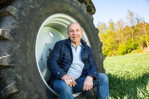 Landesrat Max Hiegelsberger sitzt in der Felge eines Traktorreifens 