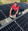 Landesrat Markus Achleitner mit Betonstein in Händen auf einem Flachdach voller Solarmodule