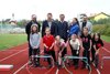 Martin Bernecker, Gerhard Kronsteiner, Landesrat Markus Achleitner, Bettina Hötzenegger mit Baby am Arm und  Andreas Derntl stehen nebeneinander auf der Laufbahn eines Sportplatzes, vor ihnen sechs Kinder in Laufstart-Position