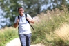 Landesrat Markus Achleitner mit Rucksack beim Wandern auf einem Weg in einer Landschaft mit Sträuchern und Bäumen