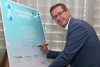 LR Landesrat Markus Achleitner steht vor einer Tafel und unterzeichnet ein Manifest im Rahmen der Landesenergiereferenten-Konferenz in Linz im September des Vorjahres, dahinter ein Fenster mit Vorhang.