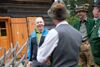 Landesrat Max Hiegelsberger im Gespräch mit den Bewirtschaftern der Hinteren Sandlingalm stehend vor einer Hütte auf der Alm.