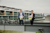 Landesrat Stefan Kaineder und Eva Schobesberger stehen nebeneinander auf einem Schiffs-Zugang über dem Fluss, im Hintergrund  ein Donau-Kreuzfahrtschiff