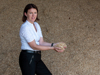Landesrätin Michaela Langer-Weninger hält Holzspäne in Händen, im Hintergrund ein großer Haufen mit Spänen