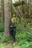 Landesrätin Michaela Langer-Weninger lehnt in einem Wald an einem Baum, hinter ihr ein Jägerstand