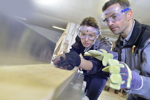 Lehrling und Ausbildner beim Schleifen von Holz