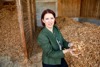 Landesrätin Michaela Langer-Weninger steht in einem Lager, in dem sich große Haufen mit Holzspänen befinden und hält Holzspäne in Händen