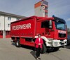 Feuerwehr-Landesrätin Michaela Langer-Weninger steht im Freien vor einem Einsatzwagen der Feuerwehr, im Hintergrund Feuerwache. 