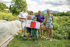 Umwelt- und Klima-Landesrat Stefan Kaineder steht mit drei erwachsenen Personen und zwei Kindern vor einem Gemüsebeet; die beiden Kinder halten den Siegerscheck gemeinsam hoch. 