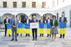 MFG-Klubobmann Manuel Krautgartner. Dritter Präsident Peter Binder, Neos-LAbg. Dr.in Julia Bammer, FPÖ-Klubobmann Ing. Herwig Mahr, LT-Präs. Max Hiegelsberger,  SPÖ-Klubobmann Mag. Michael Lindner, Grüne-Klubobmann Severin Mayr, Zweite Präsidentin Sabine Binder und ÖVP-Klubobmann Dr. Christian Dörfel stehen im Innenhof des Landeskulturzentrums Ursulinenhof nebeneinander und sie halten gemeinsam eine Ukrainische Flagge; LT-Präs. Max Hiegelsberger hält eine Tafel mit den Worten „Gemeinsame Erklärung“ in den Händen 