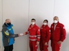 Impfstoffübergabe, drei Personen vom Roten Kreuz wird eine Schachtel übergeben